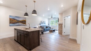 A spacious kitchen with a large island, pendant lighting, and a dining area with a sofa and coffee table. - In the Heart Of Keystone, Mountain Views from Private Balcony! (Keystone)
