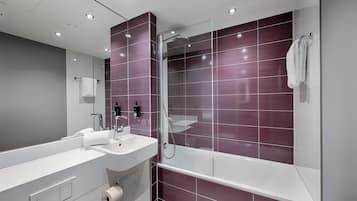 Un baño moderno con un espejo grande, dos lavamanos, una ducha y un inodoro.