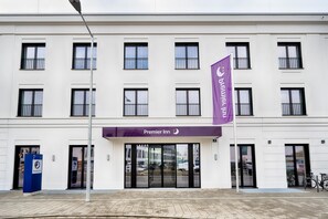 A hotel entrance with a prominent 'Premier Inn' sign, a flag, and a blue information board. - Premier Inn Regensburg City Centre (Regensburg)
