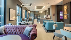 A modern hotel lobby with a plush seating area, a bar, and a reception desk. - Premier Inn Regensburg City Centre (Regensburg)