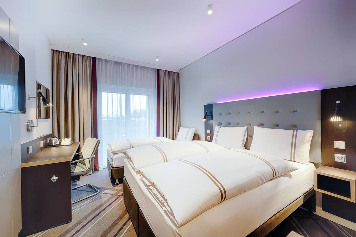 Una habitación de hotel con una cama grande, un escritorio, una silla, un televisor y una mesita de noche.