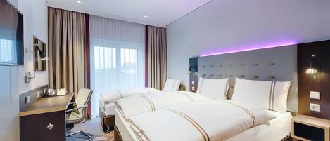 Una habitación de hotel con una cama grande, un escritorio, una silla, un televisor y una mesita de noche.