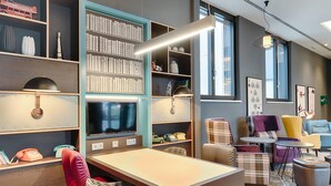 A modern library with bookshelves, a television, and comfortable seating areas. - Premier Inn Regensburg City Centre (Regensburg)