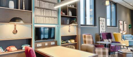 Una biblioteca moderna con estanterías, televisión y zonas de estar cómodas.