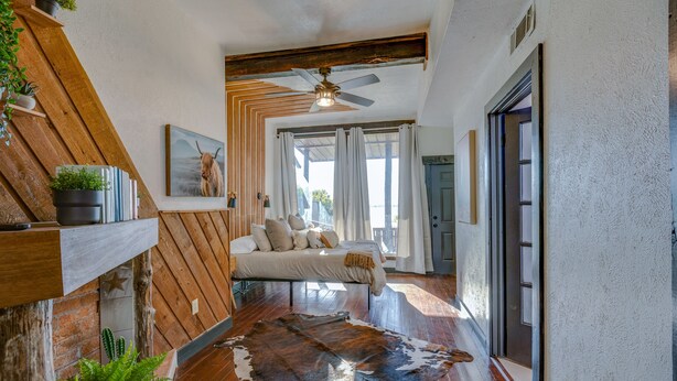 A room with a bed, a ceiling fan, a cowhide rug, and a wooden wall. - Lakefront Estate With 2 Kitchens Perfect for Events & Families (Nevada)