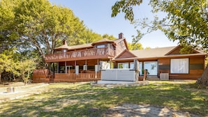A two-story wooden house with a balcony, a covered porch, and a garage. - Lakefront Estate With 2 Kitchens Perfect for Events & Families (Nevada)