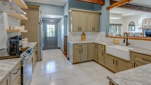 A modern kitchen with light wood cabinets, a large island, and a built-in oven. - Lakefront Estate With 2 Kitchens Perfect for Events & Families (Nevada)