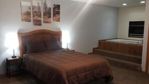 A bedroom with a bed, bedside tables, a nightstand, a window, and a bathroom with a bathtub. - Private Downtown Apt, King Bed, Jet Bath, Fireplace, Grill, near Indiana Dunes (Chesterton)