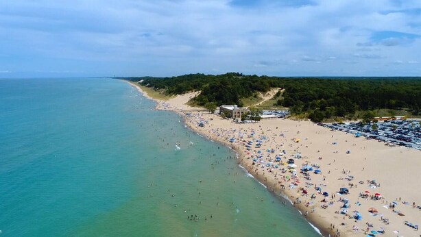 A beach with a parking lot and a building with a sloped roof. - Private Downtown Apt, King Bed, Jet Bath, Fireplace, Grill, near Indiana Dunes (Chesterton)