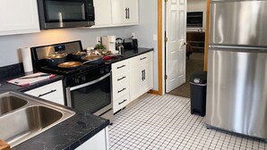A modern kitchen with white cabinets, a stainless steel refrigerator, a microwave, and a stove. - Private Downtown Apt, King Bed, Jet Bath, Fireplace, Grill, near Indiana Dunes (Chesterton)