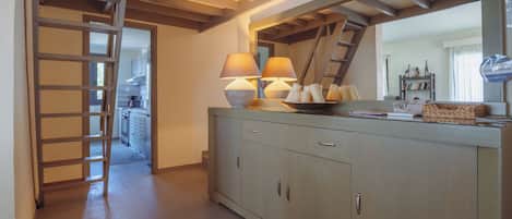 A kitchen with a wooden staircase, a counter with two lamps, and a mirror above it.
