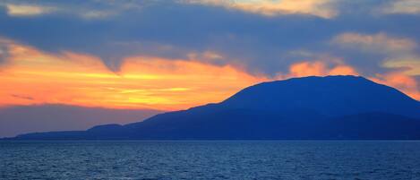La silhouette d’une montagne se découpant sur le ciel au coucher du soleil, au-dessus d’une mer calme.