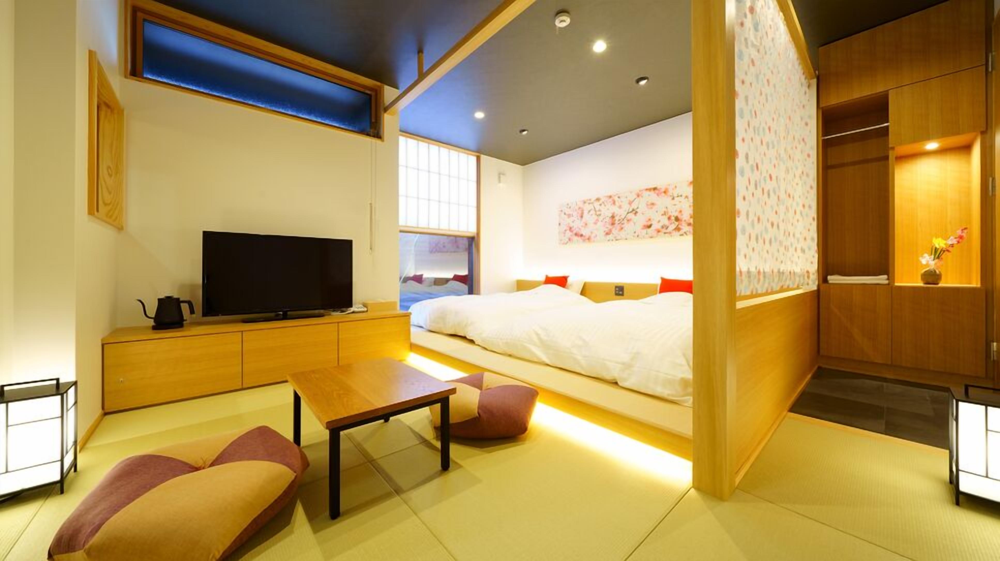 A modern hotel room with a bed, TV, wooden furniture, and a view of the city.