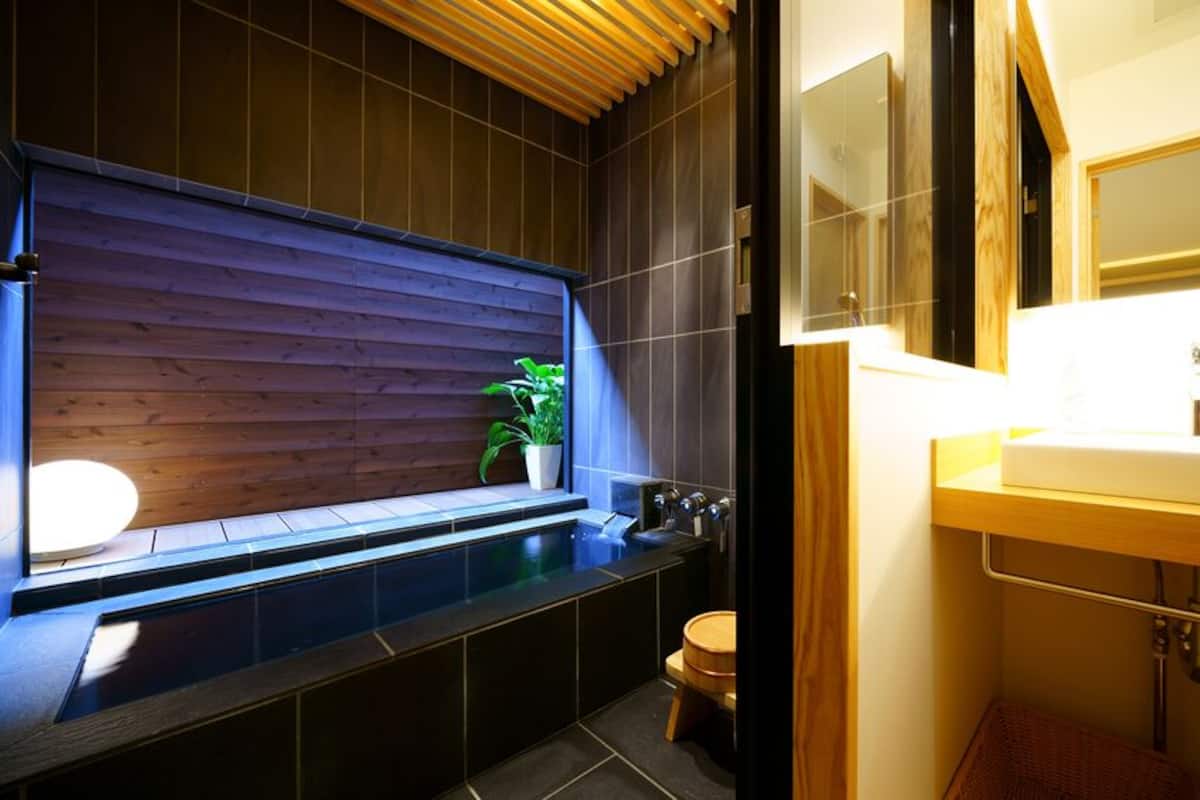 A modern bathroom with a wooden panel wall, a built-in bathtub, a sink, and a toilet.