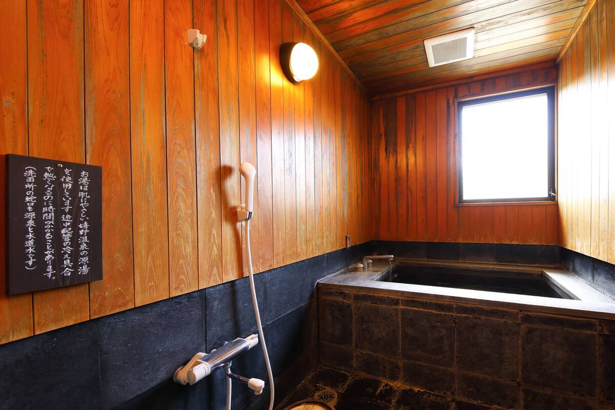 A wooden interior with a stone bathtub, a wooden bench, and a window.