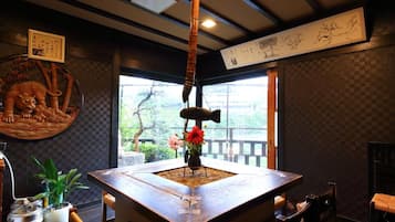 A traditional Japanese room with tatami flooring, a low table with a vase of flowers, and a hanging scroll on the wall.