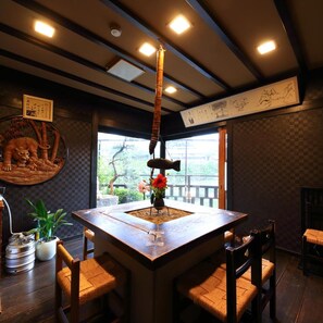 A traditional Japanese room with tatami flooring, a low table with a vase of flowers, and a hanging scroll on the wall. - Ureshino Onsen Takasago (Ureshino)