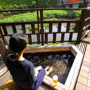 A person sitting by a wooden pool with a drink, overlooking a river and greenery. - Ureshino Onsen Takasago (Ureshino)
