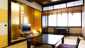 A traditional Japanese room with tatami flooring, a low table, and a television.
