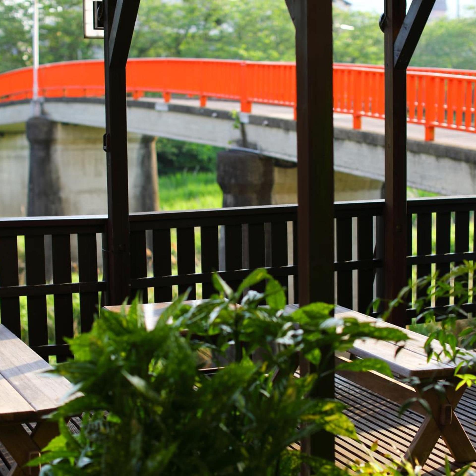 Un espacio de descanso al aire libre con techo, que ofrece vistas a un puente y follaje.