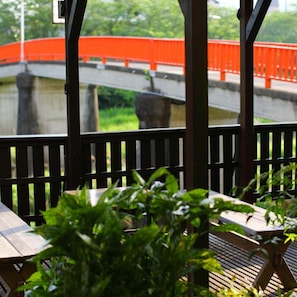 A covered outdoor seating area with a view of a bridge and greenery. - Ureshino Onsen Takasago (Ureshino)