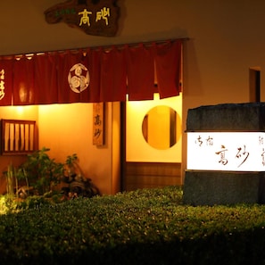 A traditional Japanese entrance with a red awning, a signboard with Japanese characters, and a small garden area in front. - Ureshino Onsen Takasago (Ureshino)
