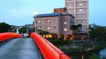 Un puente con barandilla roja que lleva a un edificio con múltiples ventanas y un letrero arriba.