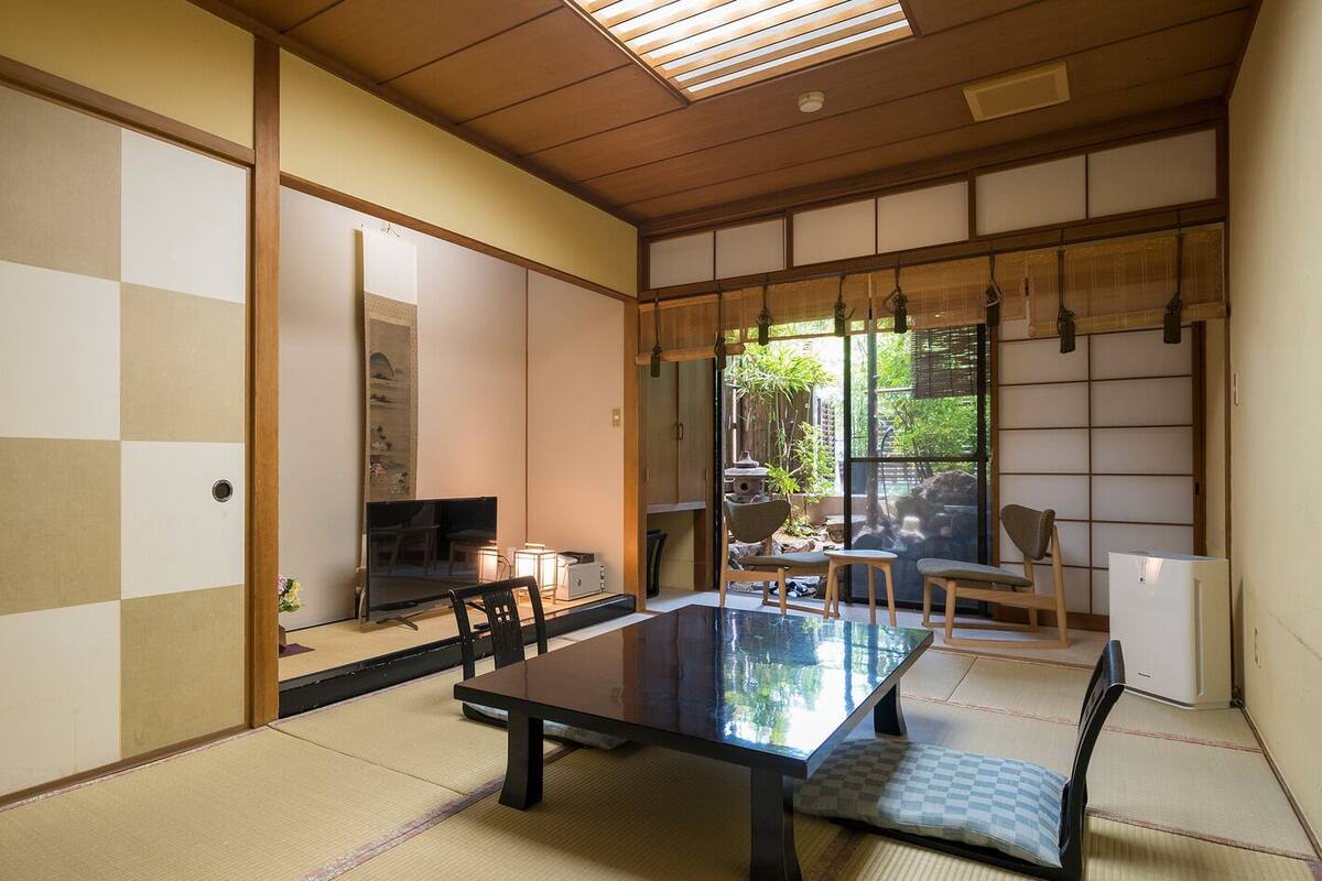 A traditional Japanese room with tatami flooring, a low table, and sliding doors.