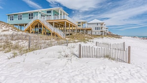 A beachfront property with elevated structures, wooden walkways, and a sandy beach.