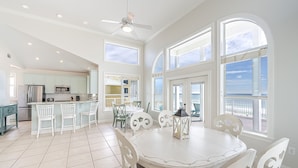 A spacious kitchen with a dining area, large windows, and a view of the ocean.