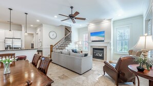 A spacious living room with a fireplace, a dining area with a wooden table, and a kitchen with modern appliances.