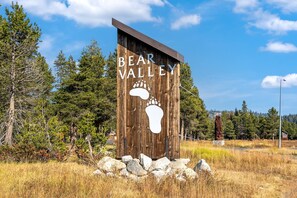 A wooden sign with the text "Bear Valley" and a footprint symbol, surrounded by rocks and grass. - Amazing Architecture - Views all around VH#113 by Bear Valley Vacation Rentals (Arnold)