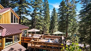 A wooden cabin with a deck, surrounded by tall pine trees. - Amazing Architecture - Views all around VH#113 by Bear Valley Vacation Rentals (Arnold)