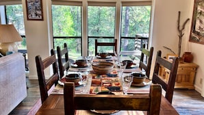 A dining table set with plates, bowls, and glasses, surrounded by wooden chairs. - In the Pines, Cozy Retreat with Amazing Views (Idyllwild)