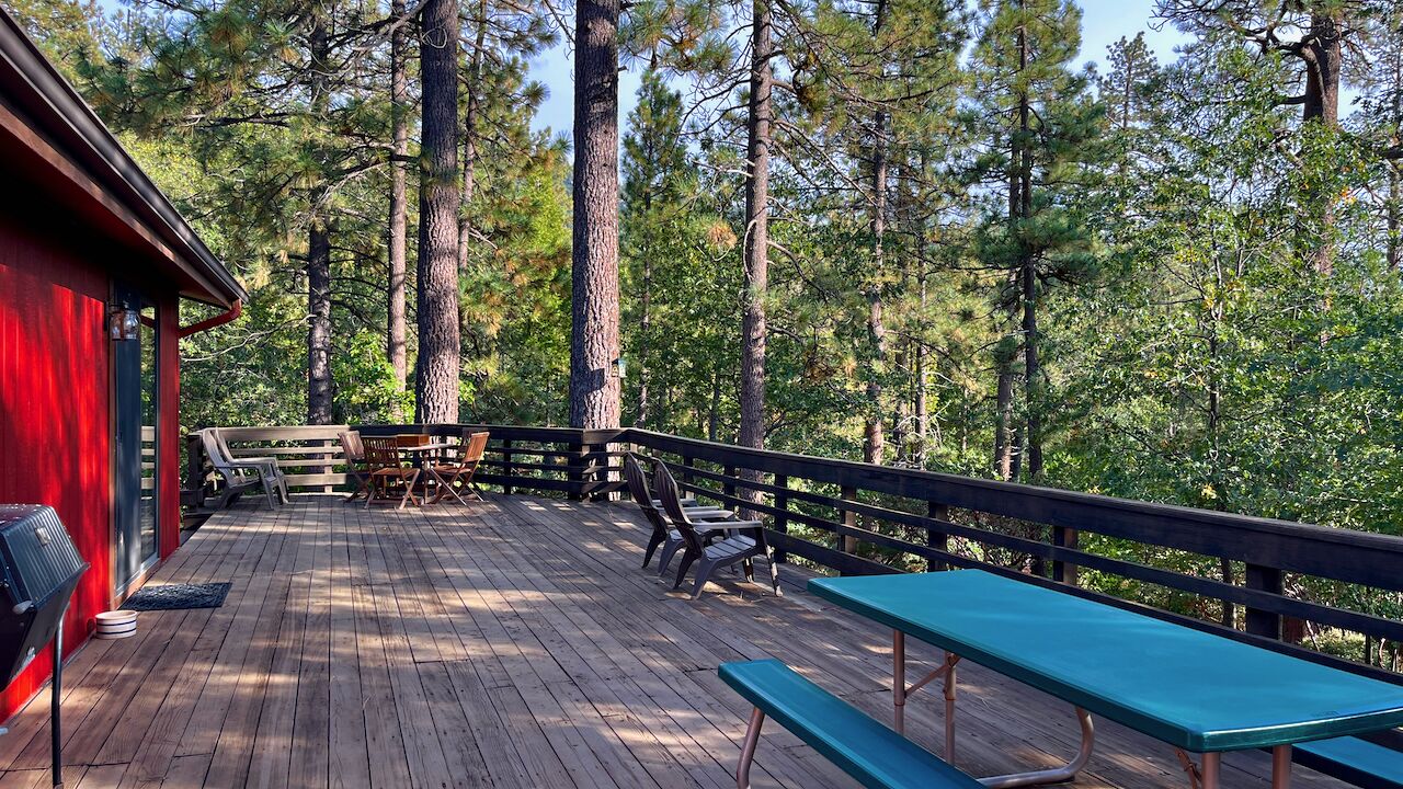 Eine Holzterrasse mit Picknicktischen und -stühlen, umgeben von hohen Kiefern.