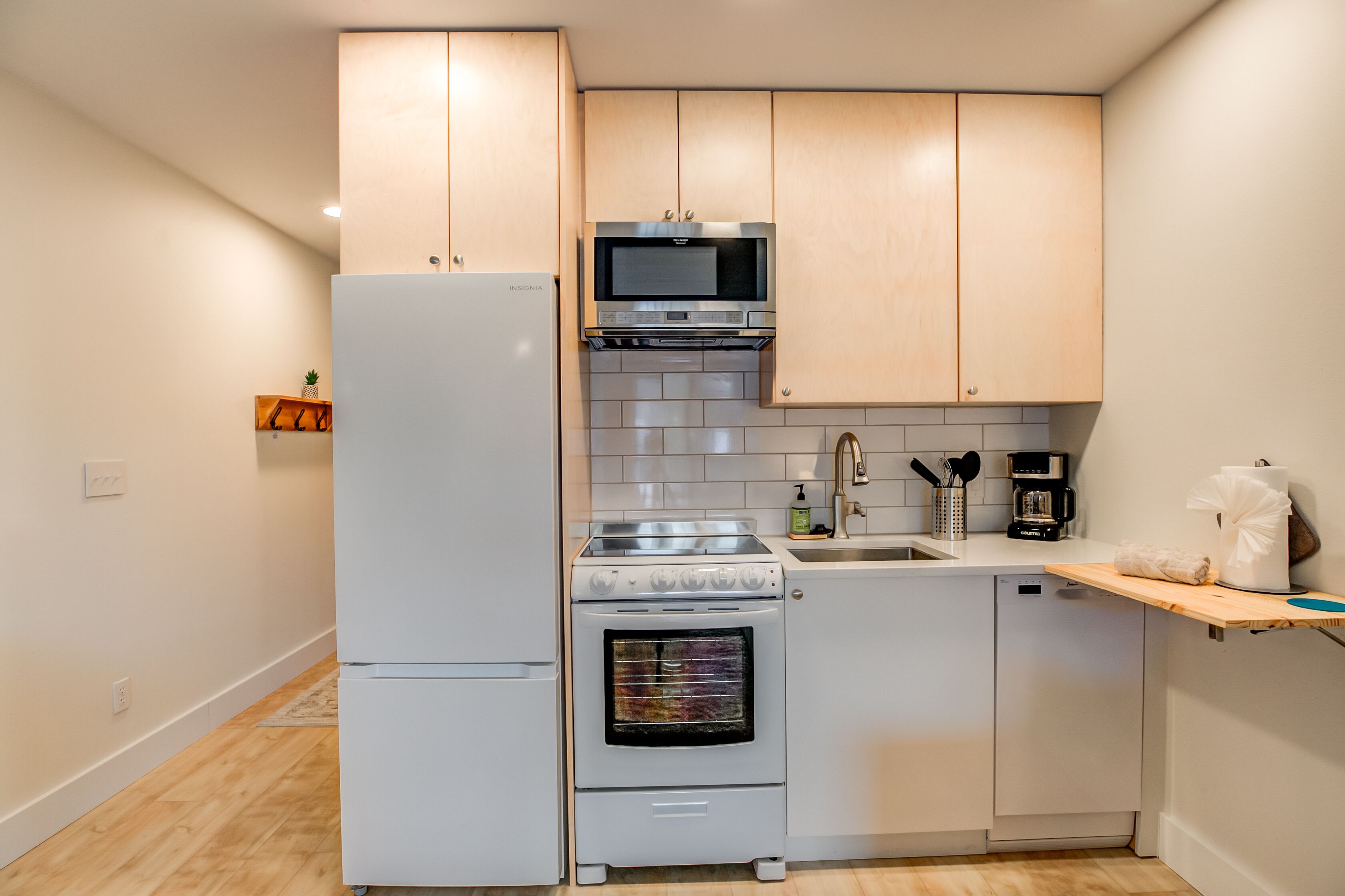 Eine kleine Küche mit Kühlschrank, Mikrowelle, Backofen und Geschirrspüler.