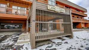 A multi-story building with a wooden facade, balconies, and a gated entrance.