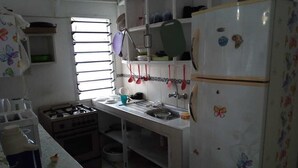 A kitchen with a gas stove, a sink, a refrigerator, and a window with blinds. - Stay.Plus Nyumba Tulivu Watamu (Watamu)