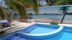 A swimming pool with a curved edge, a lounge chair, and a palm tree. - Stay.Plus Nyumba Tulivu Watamu (Watamu)