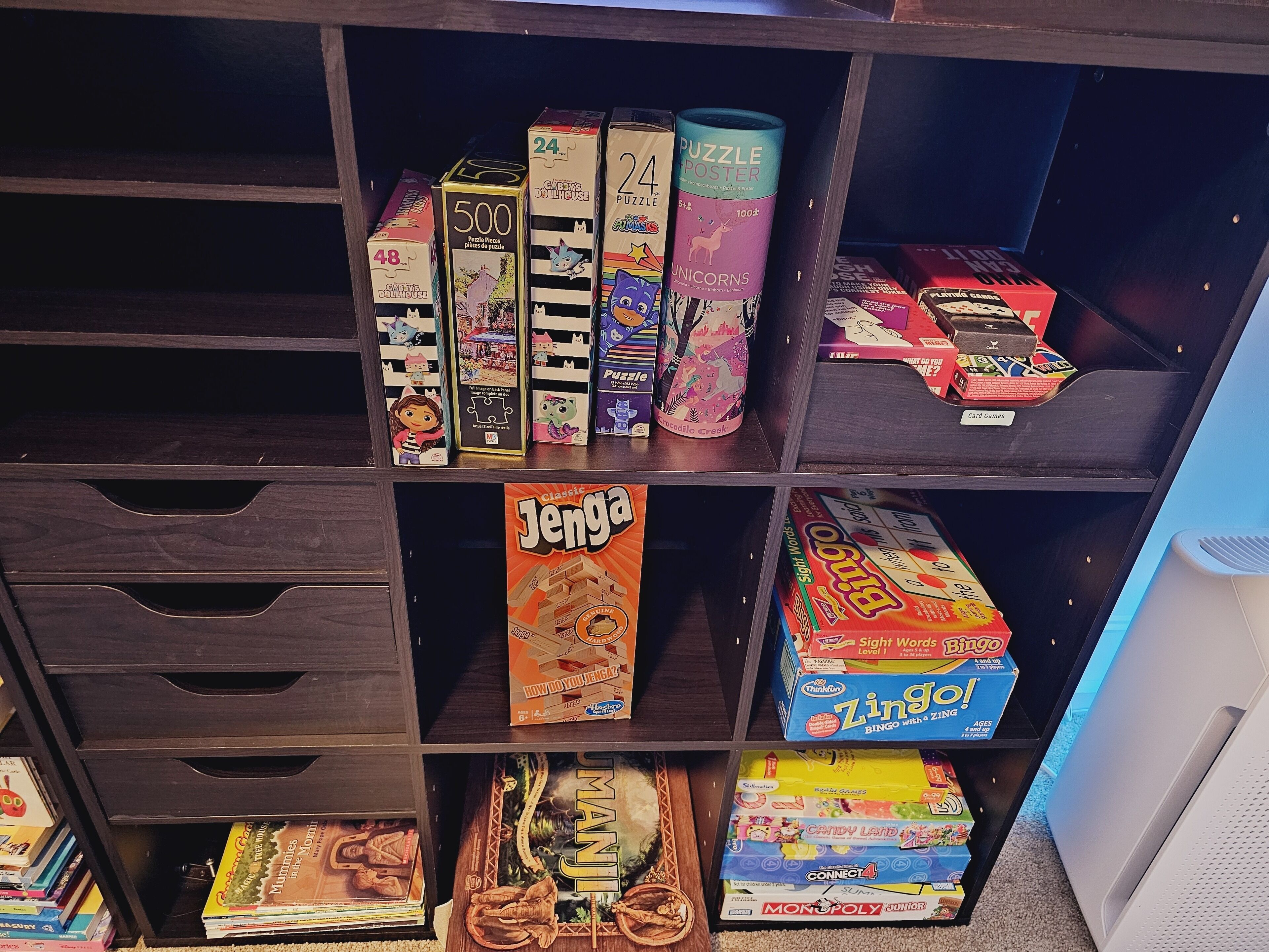 Ein Regal mit verschiedenen Gesellschaftsspielen und Puzzles, darunter Jenga, Bingo und Monopoly.