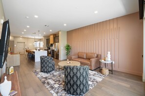 Una sala de estar moderna con un sofá, otomanas, una mesa de centro y un comedor con sillas.