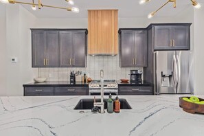 Una cocina moderna con armarios oscuros, un refrigerador de acero inoxidable y una encimera de mármol.
