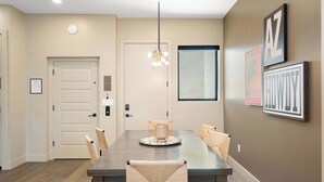 Un comedor con una mesa rectangular, seis sillas, una lámpara colgante y cuadros en las paredes.