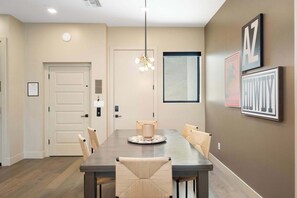 Un'area pranzo con un tavolo rettangolare, sei sedie, un lampadario e quadri appesi alle pareti.
