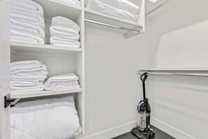 A neatly organized closet with folded towels and a vacuum cleaner. - NEW|Palo Verde Suite @ Cedara| Penthouse|Old Town (Scottsdale)