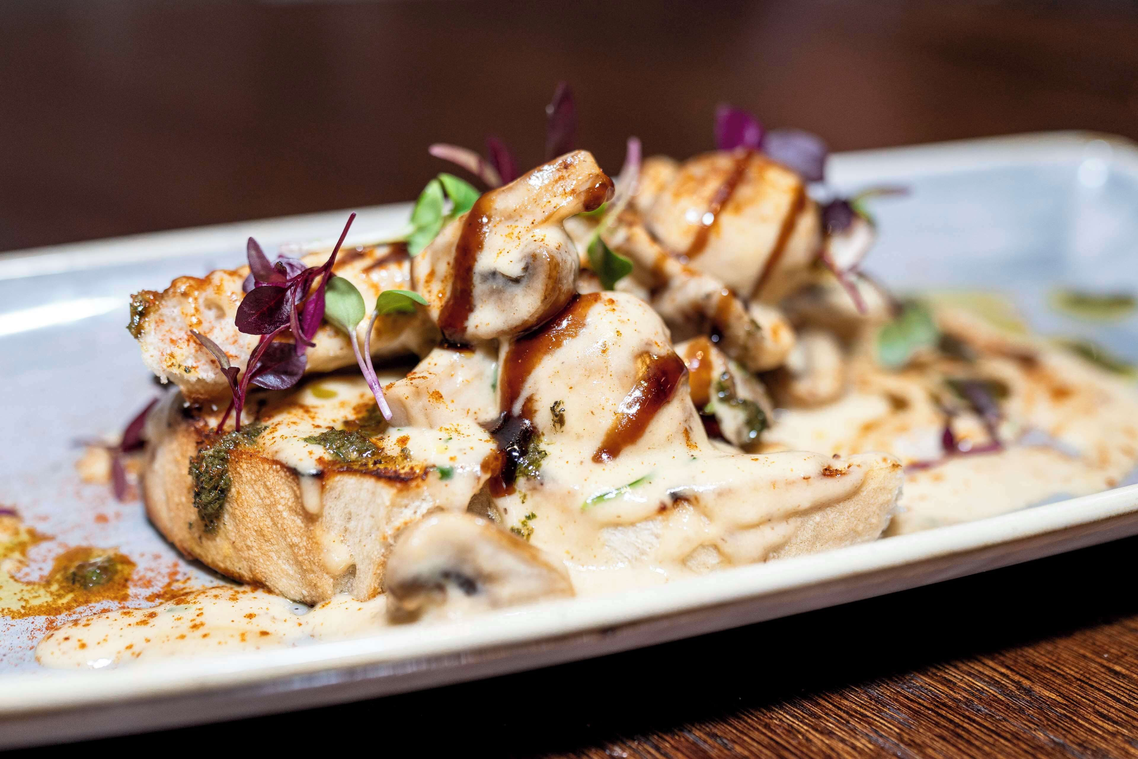A dish with chicken, mushrooms, and greens on a white plate.