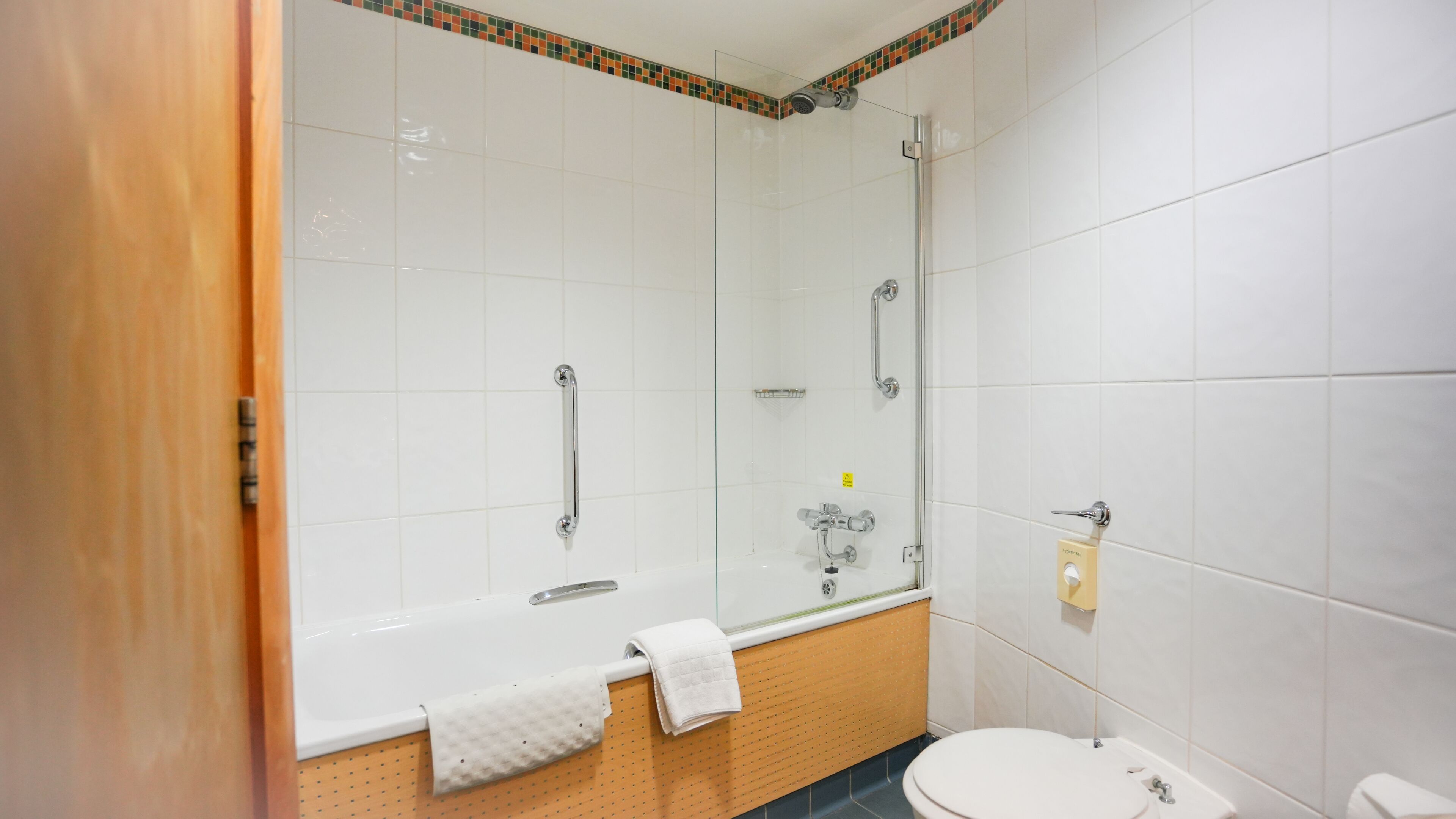 A bathroom with a bathtub, a shower, a toilet, and a towel rack.