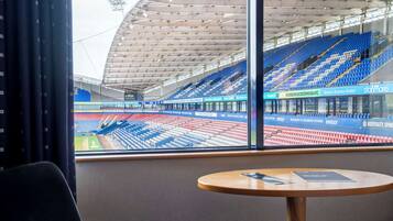 A stadium with empty blue and red seats, a large open space, and a table with a menu.