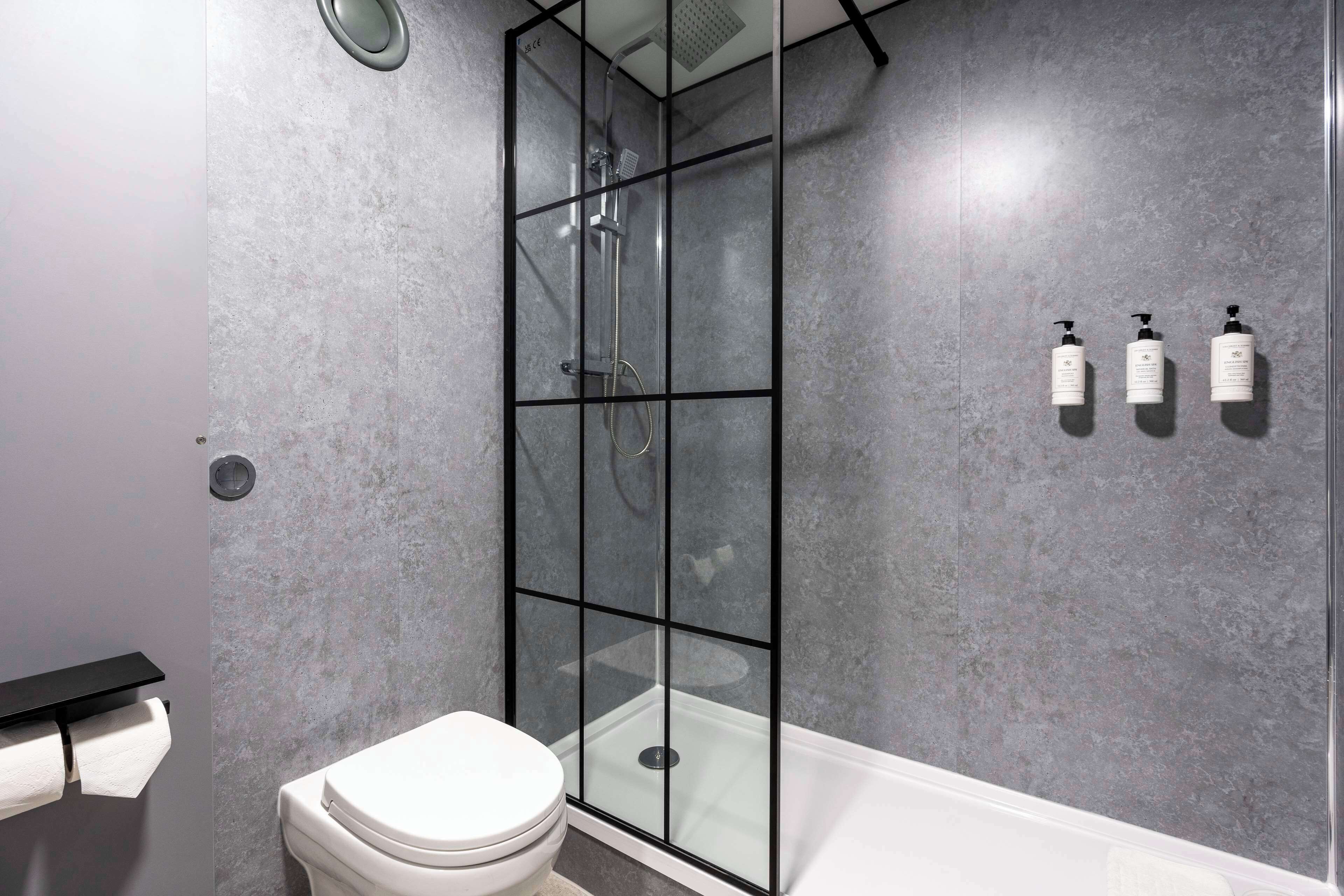 Un baño moderno con ducha de vidrio, inodoro blanco y bañera.