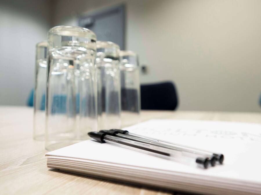 Un carnet et un stylo posés sur une table en bois, accompagnés de plusieurs bouteilles en verre transparent.